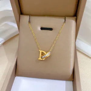 Detailed close-up of golden titanium choker with D pendant and crystal ring in a jewelry box