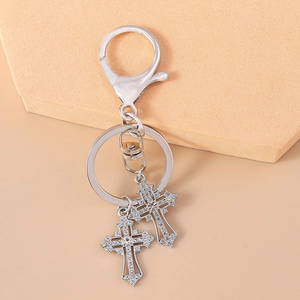 Detail of silver gothic cross keychain with sparkling rhinestones on geometric backdrop