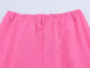 Détail du pantalon en lin rose avec taille élastique et passants de ceinture sur fond blanc