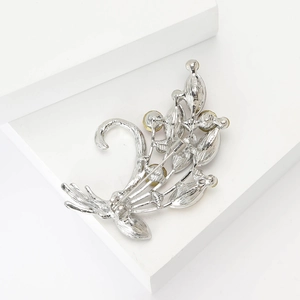 Detail of silver alloy bouquet brooch with yellow round gemstones on white pedestal