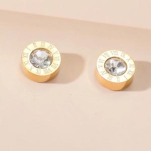 Macro detail of gold-plated roman numeral stud earring with central faceted crystal stone