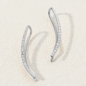 Detail view showing the unique hammered texture and curved design of silver ear climbers