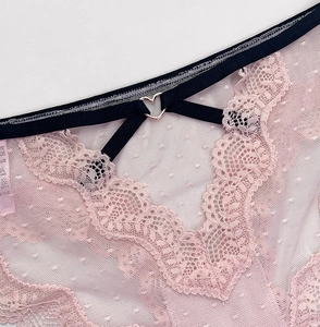 Close-up of pink lace panties with polka dot mesh and a heart-shaped metal ring detail