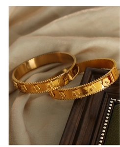 Detail of 18K gold plated flower bangles with embossed floral patterns and milgrain edges