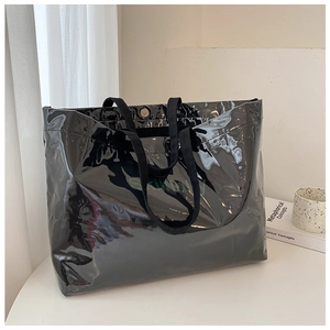 Close-up of black glossy patent leather tote bag with large capacity and logo detail