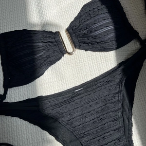 Close-up of black bikini with wave texture fabric and golden U-shaped metal hardware