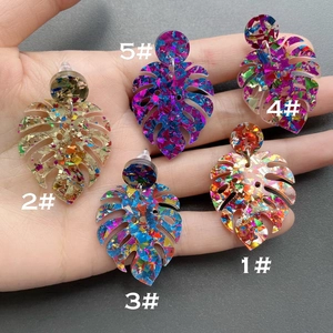 Close-up of five colorful monstera leaf acrylic earrings with sparkling glitter foil