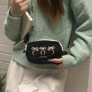 Detail der schwarzen Stepptasche mit rosa bestickten Schleifen und Reißverschluss