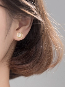 Close-up of sparkling square zircon stud earrings with gold plating on a model ear