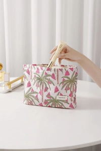 Close-up of jacquard fabric makeup bag with coconut tree pattern and gold skincare tube