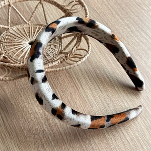 Detail of leopard print velvet headband with padded sponge design on wooden surface