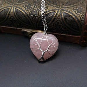 Detailed close-up of wire-wrapped rose quartz heart pendant with tree of life design