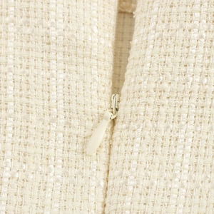 Gros plan sur la texture du tissu en tweed beige et la fermeture éclair invisible du set
