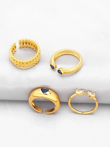 Detailed macro view of four adjustable gold-plated rings with blue heart-shaped gems
