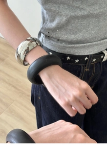 Close-up of chunky polished silver and matte black minimalist bangles on wrist