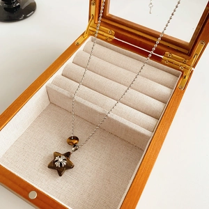 Detail of cross necklace with heart resin pendant resting in a wooden jewelry box
