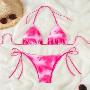 Pink and white tie-dye bikini set with halter top and side-tie bottoms on beach props