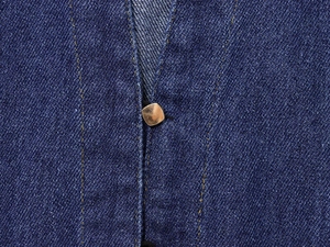 Dettaglio del tessuto denim blu con bottoni metallici quadrati dorati e cuciture