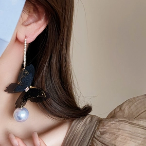 Detail of elegant black mesh butterfly earrings with sparkling crystals and large pearl drop