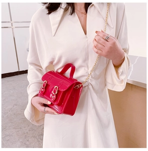 Glossy red jelly crossbody bag in a classic Cambridge satchel style worn by model