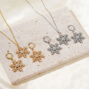 Detailed view of snowflake necklace and earring sets in gold and silver finishes