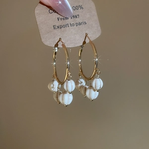 Detailed close-up of vintage gold hoop earrings with white stone tassels and bead accents
