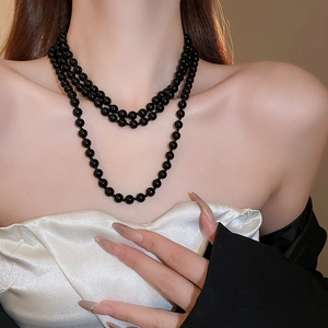 Detailed view of layered black faux pearl necklace with triple-strand glossy beads finish