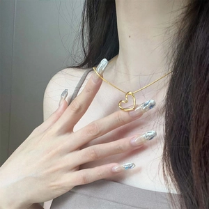 Detailed view of a golden hollow heart pendant necklace worn on a female neck for fashion