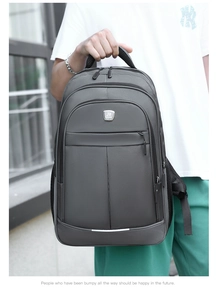 Dark gray business laptop backpack held by a model in a modern urban outdoor setting