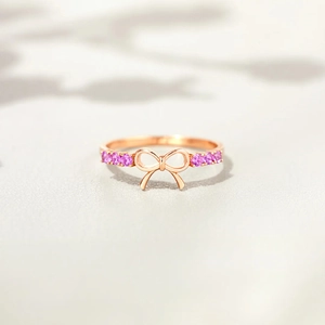 Elegant rose gold bow ring for women featuring purple zircon accents on a gray surface