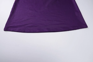 Detailed view of the sewing craftsmanship and hemline on a purple summer dress fabric