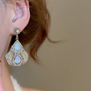 Detailed close-up of teardrop earrings with blue and yellow crystals on ear