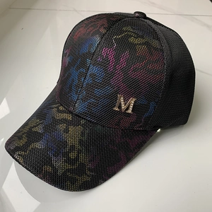Detail of black mesh baseball cap with colorful graffiti patterns and a gold rhinestone M logo