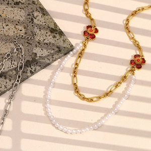 Close-up of 18K gold plated pearl flower double necklace with shadow on textured background