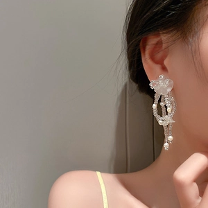 Detail of long floral fringe earrings with white resin flowers and pearl tassels