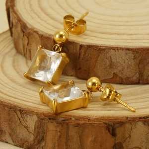 Macro shot of 18K gold plated earrings with square cubic zirconia on a rustic wood base