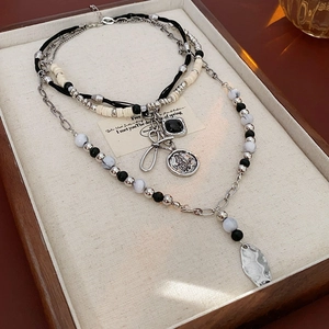 Detail of bohemian layered necklace with butterfly pendant and beads in a wooden box