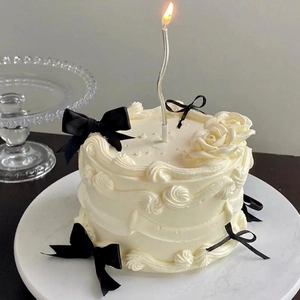 Gâteau vintage blanc élégant avec nœuds en satin noir et bougie spirale argentée