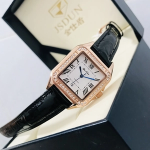 Macro view of a square gold watch with diamond bezel and black leather strap in a gift box