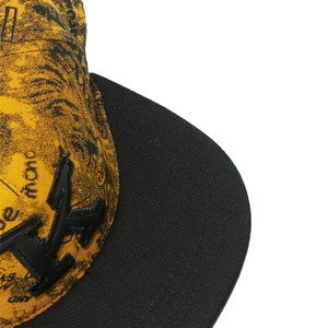 Detail of Compton hip hop cap with TK 3D embroidery and graffiti print on yellow fabric