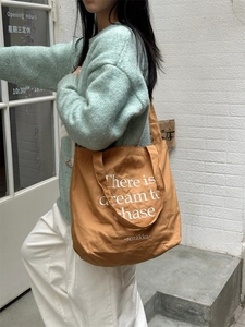 Close-up of brown canvas tote bag with white lettering for women daily leisure