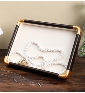 Macro detail of luxury walnut jewelry tray with gold corners and beige velvet lining
