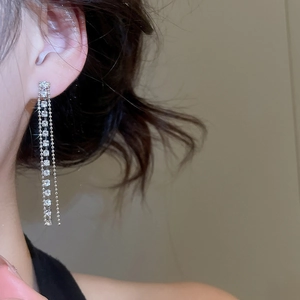 Dettaglio di eleganti orecchini a nappa d'argento con strass scintillanti su modella