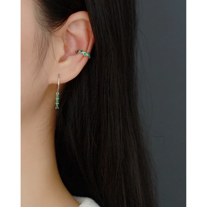 Detail of s925 silver hoop earring set with green zircon on female model's ear