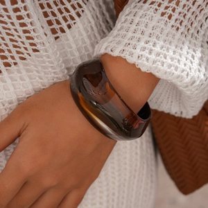 Macro shot of translucent amber acrylic cuff bracelet with butterfly relief on wrist