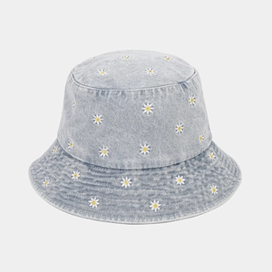 Detail of white daisy floral embroidery on a light blue washed denim bucket hat