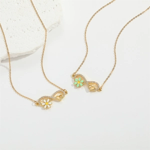 Golden stainless steel heart and infinity flower pendant necklace on white background