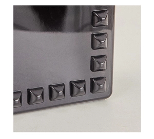 Macro shot of dark grey PVC tote bag featuring metallic pyramid stud edge detailing