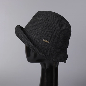 Close-up of black knitted sun hat featuring a gold metal brand tag and woven texture
