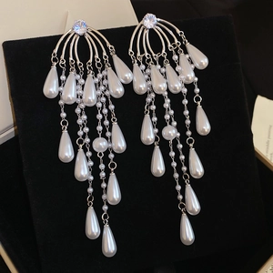 Detailed view of silver zircon drop earrings with cascading white tassels and faux pearls